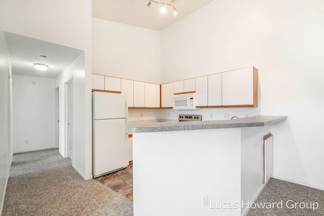 kitchen featuring light carpet, white appliances, a high ceiling, a peninsula, and light countertops