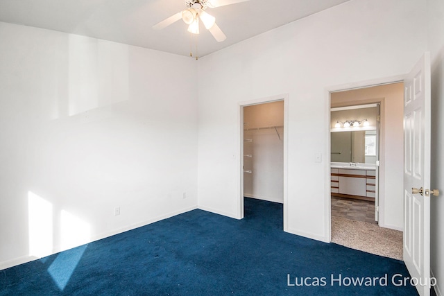 unfurnished bedroom featuring a spacious closet, dark carpet, and ceiling fan