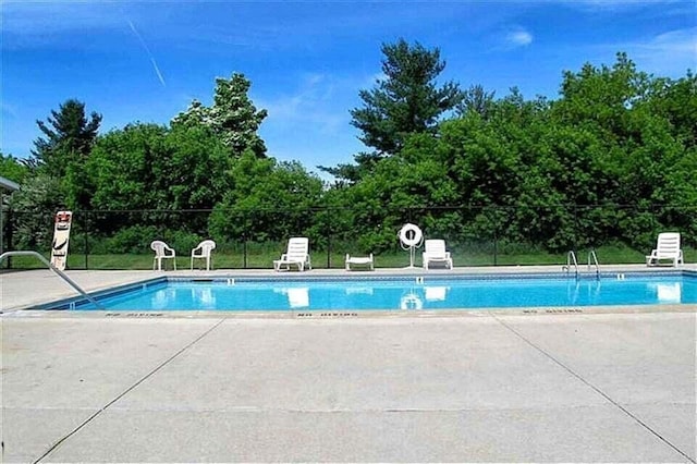 community pool with a patio and fence