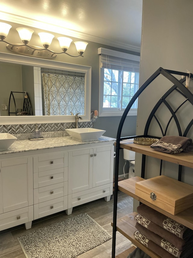 full bathroom with a sink, backsplash, wood finished floors, and double vanity