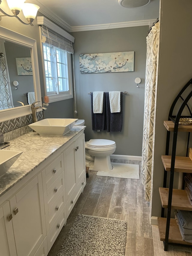 full bathroom with toilet, a sink, wood finished floors, crown molding, and baseboards