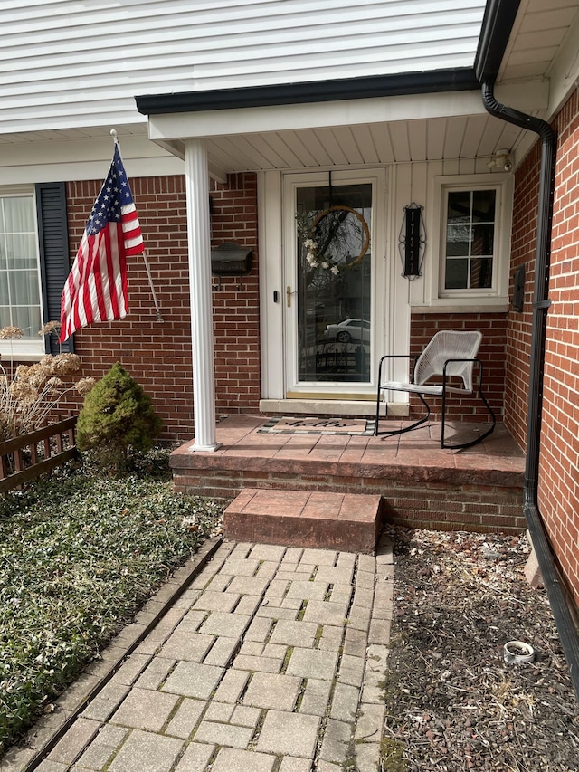 property entrance with brick siding and covered porch