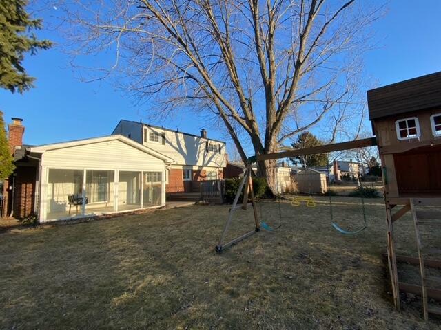 view of yard with a playground, fence, and a sunroom