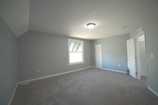 unfurnished bedroom with visible vents, lofted ceiling, baseboards, and carpet floors