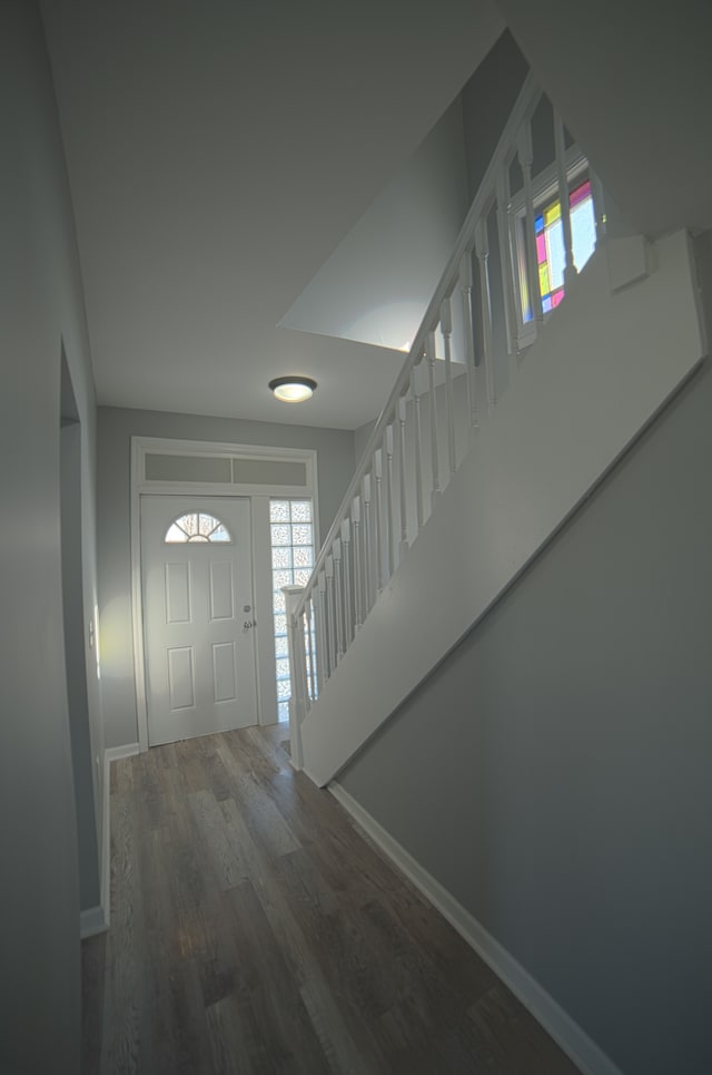 foyer entrance with stairway, baseboards, and wood finished floors