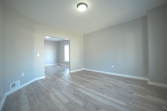 unfurnished room featuring wood finished floors, visible vents, and baseboards