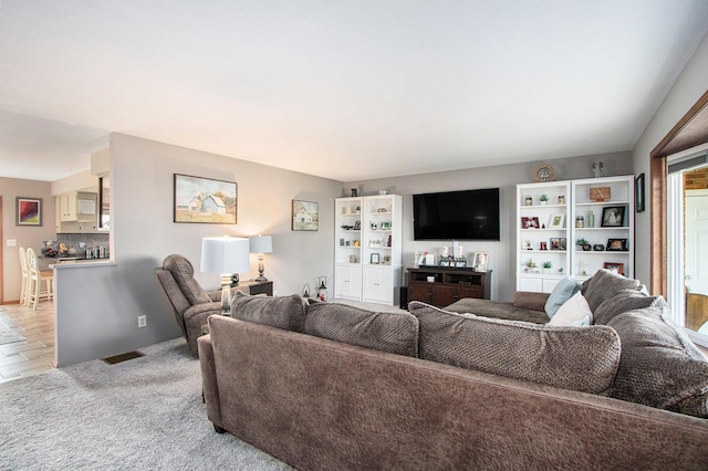 living room featuring visible vents, light colored carpet, and bar