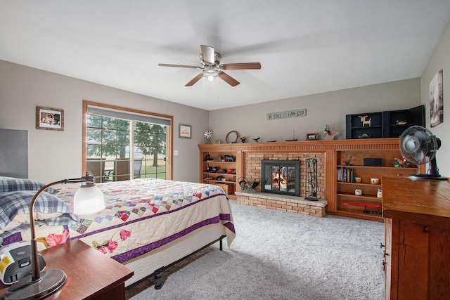bedroom with access to exterior, a brick fireplace, ceiling fan, and carpet floors