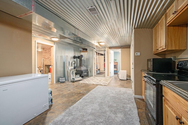 kitchen featuring dark countertops, black appliances, and a wood stove
