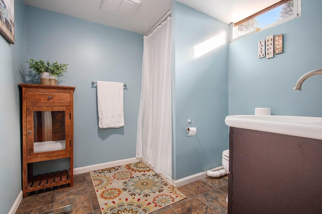 full bath featuring a shower with shower curtain, baseboards, visible vents, stone finish flooring, and toilet