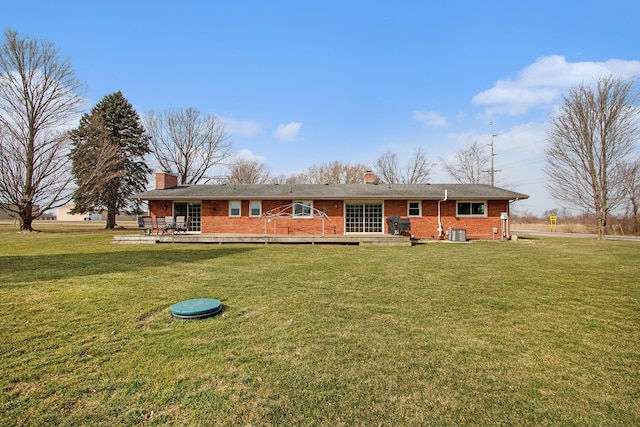view of front facade featuring a wooden deck, brick siding, a front yard, and a chimney