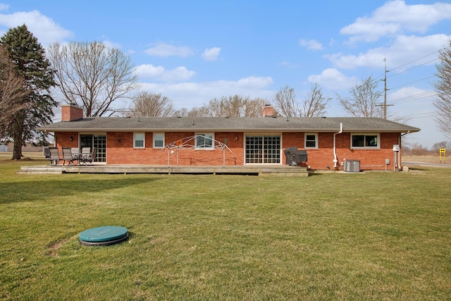 rear view of house featuring brick siding, central AC unit, and a chimney
