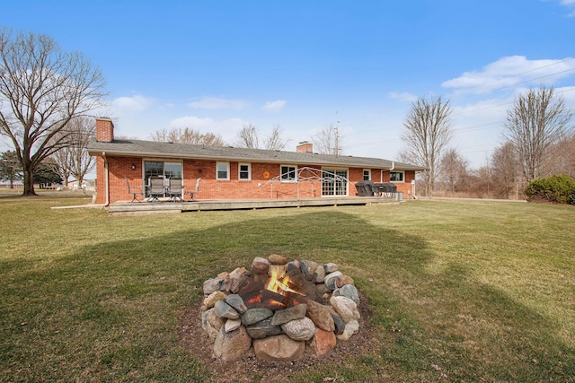 back of property with a deck, a yard, brick siding, and a chimney