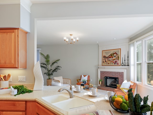 kitchen with a sink, a brick fireplace, a healthy amount of sunlight, and light countertops