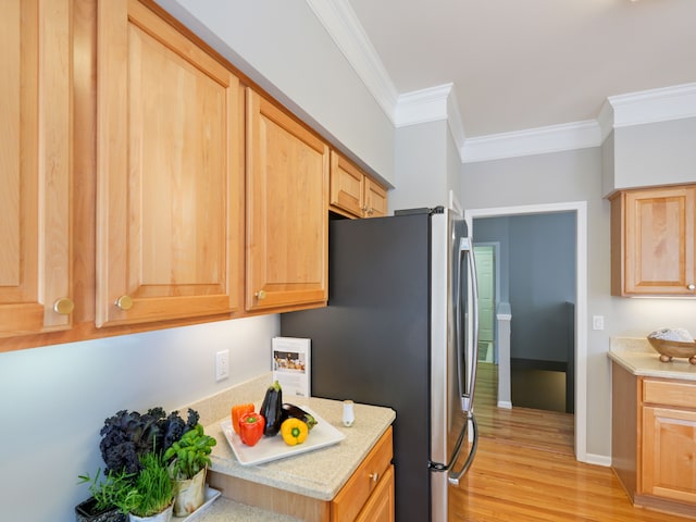 kitchen with light wood-type flooring, light countertops, freestanding refrigerator, and ornamental molding