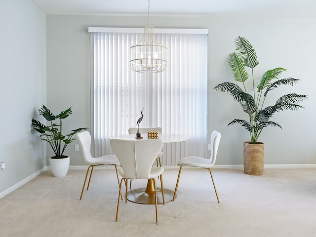 dining area featuring plenty of natural light, carpet flooring, baseboards, and an inviting chandelier