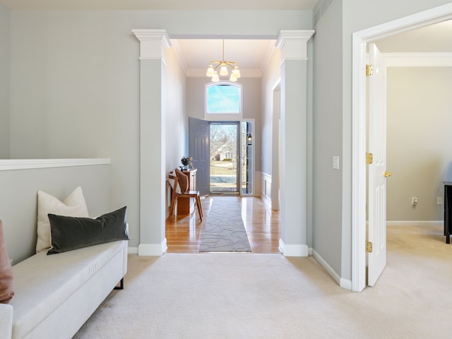 foyer with a notable chandelier, light colored carpet, crown molding, and baseboards