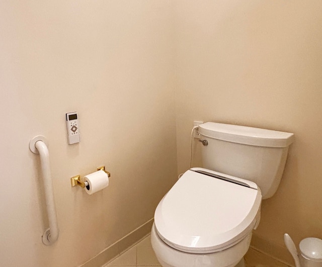 bathroom with baseboards, toilet, and tile patterned flooring