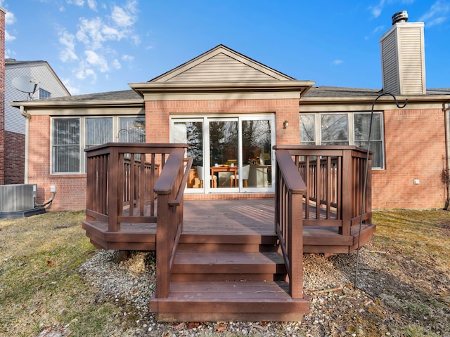 rear view of property featuring brick siding, central air condition unit, a chimney, and a wooden deck