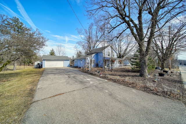 view of front of house featuring aphalt driveway, a detached garage, and a front yard