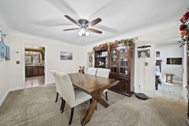 dining space featuring light colored carpet, visible vents, baseboards, and a ceiling fan