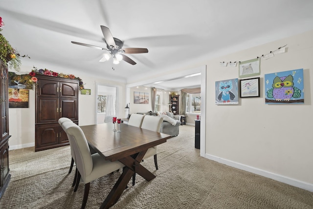 dining space featuring baseboards, light carpet, and ceiling fan
