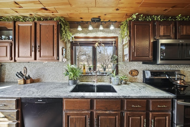 kitchen with backsplash, appliances with stainless steel finishes, light stone countertops, and a sink
