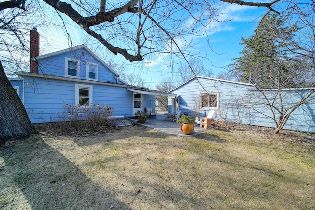 rear view of property with a chimney, a patio area, and a yard