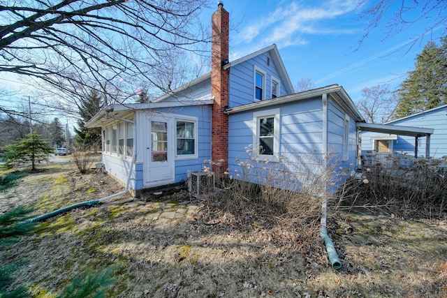 back of house featuring a chimney and central AC
