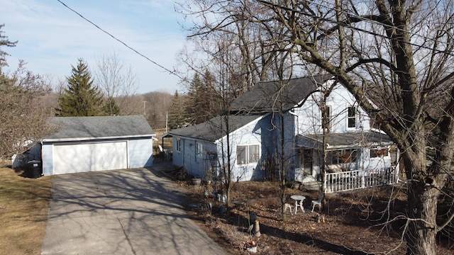 view of side of home featuring a shingled roof, an outbuilding, covered porch, and a detached garage