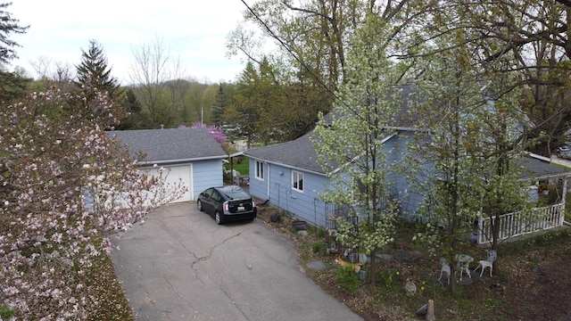view of side of property featuring roof with shingles and aphalt driveway