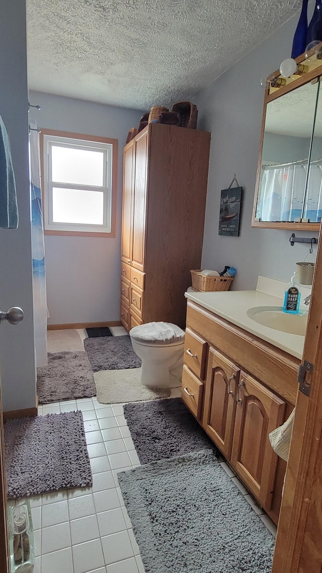 full bath featuring tile patterned flooring, a textured ceiling, toilet, and vanity