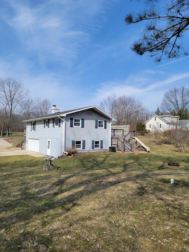 back of house featuring a garage, a lawn, a chimney, and stairway