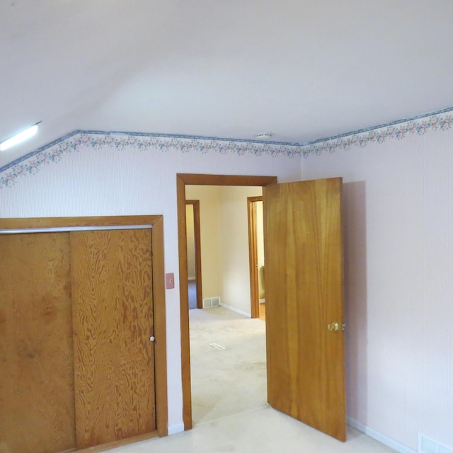 interior space featuring visible vents, light colored carpet, and vaulted ceiling