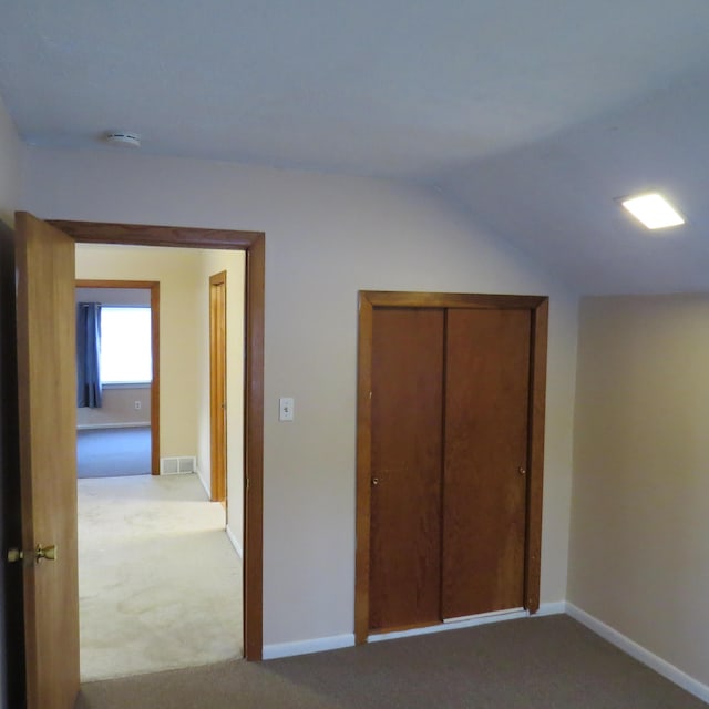 unfurnished bedroom featuring vaulted ceiling, baseboards, visible vents, and carpet floors