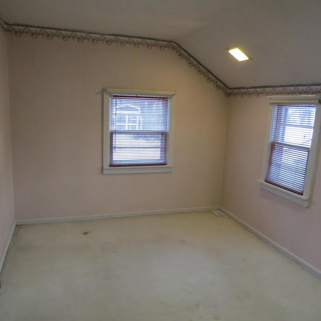 empty room featuring lofted ceiling, baseboards, and carpet floors