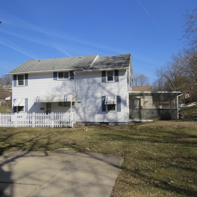 rear view of house with a lawn, roof with shingles, and fence