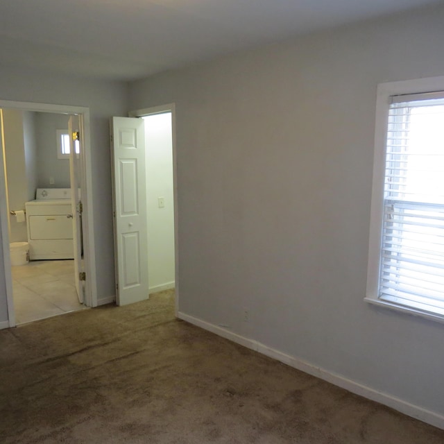 spare room featuring a wealth of natural light, baseboards, carpet, and washer / dryer