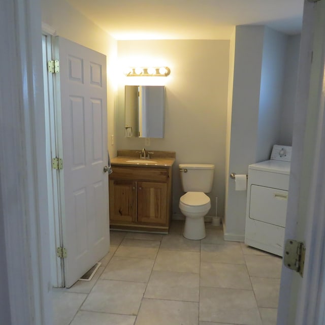 half bathroom featuring visible vents, toilet, washer / clothes dryer, tile patterned flooring, and vanity