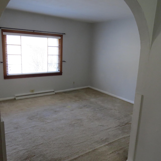 carpeted empty room featuring a baseboard radiator, arched walkways, and baseboards