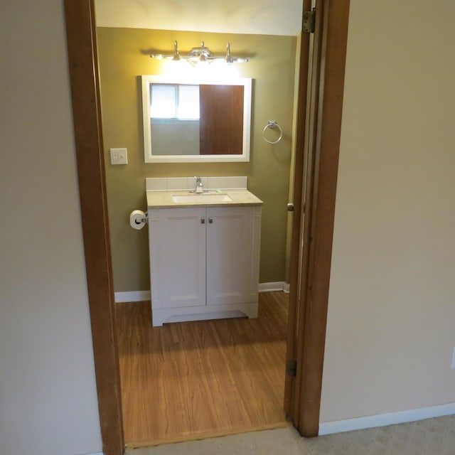 bathroom featuring baseboards, wood finished floors, and vanity