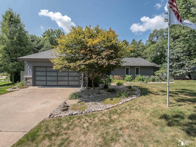 view of front of property with stone siding, a front yard, an attached garage, and driveway