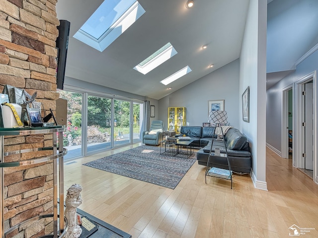 living room with a skylight, wood finished floors, baseboards, and high vaulted ceiling