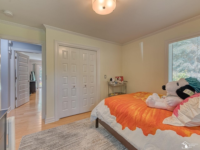 bedroom featuring a closet, light wood-style floors, and crown molding