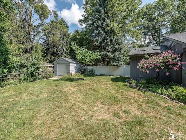 view of yard with an outbuilding, a storage unit, a garage, and fence