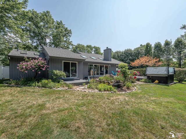 back of property with an outbuilding, a lawn, and a chimney