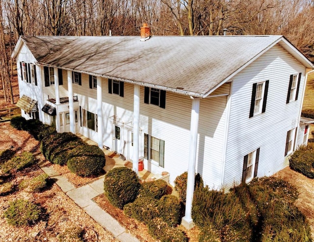 view of property exterior with a chimney and a shingled roof