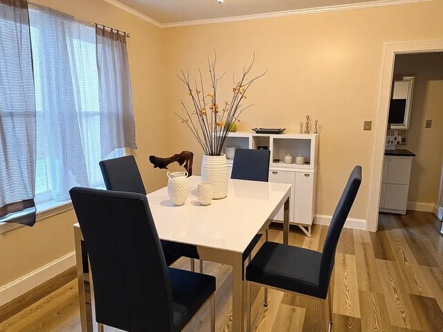 dining space with wood finished floors, baseboards, and ornamental molding
