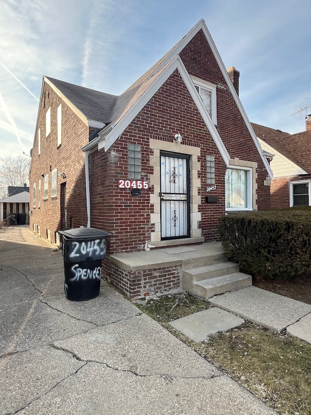 view of front of home featuring brick siding and a chimney