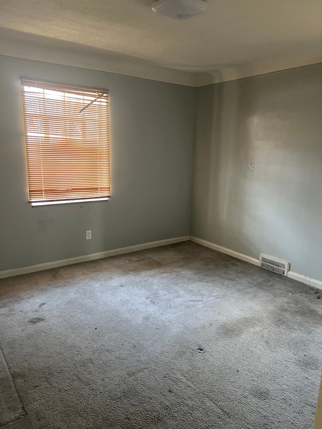 empty room featuring visible vents, carpet flooring, and baseboards